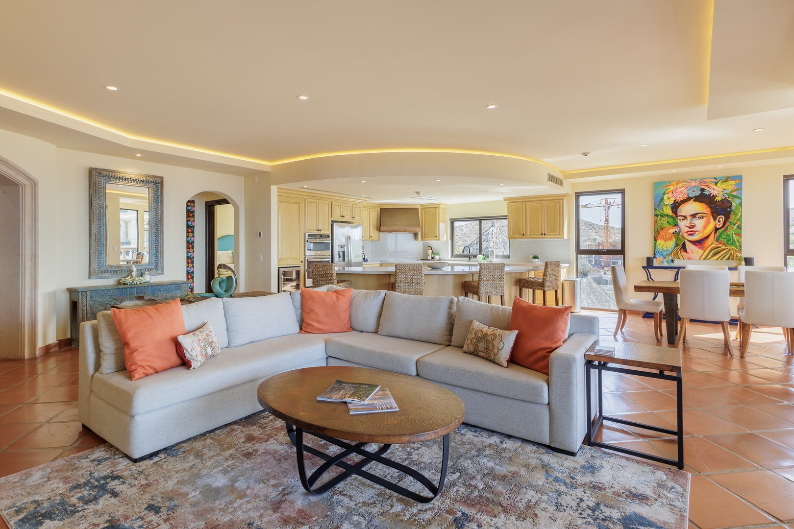 Settle into your open-concept living space with a plush sectional sofa, ambient lighting, and vibrant artwork. The seamless flow to your fully equipped kitchen and dining area invites effortless entertaining and relaxation.