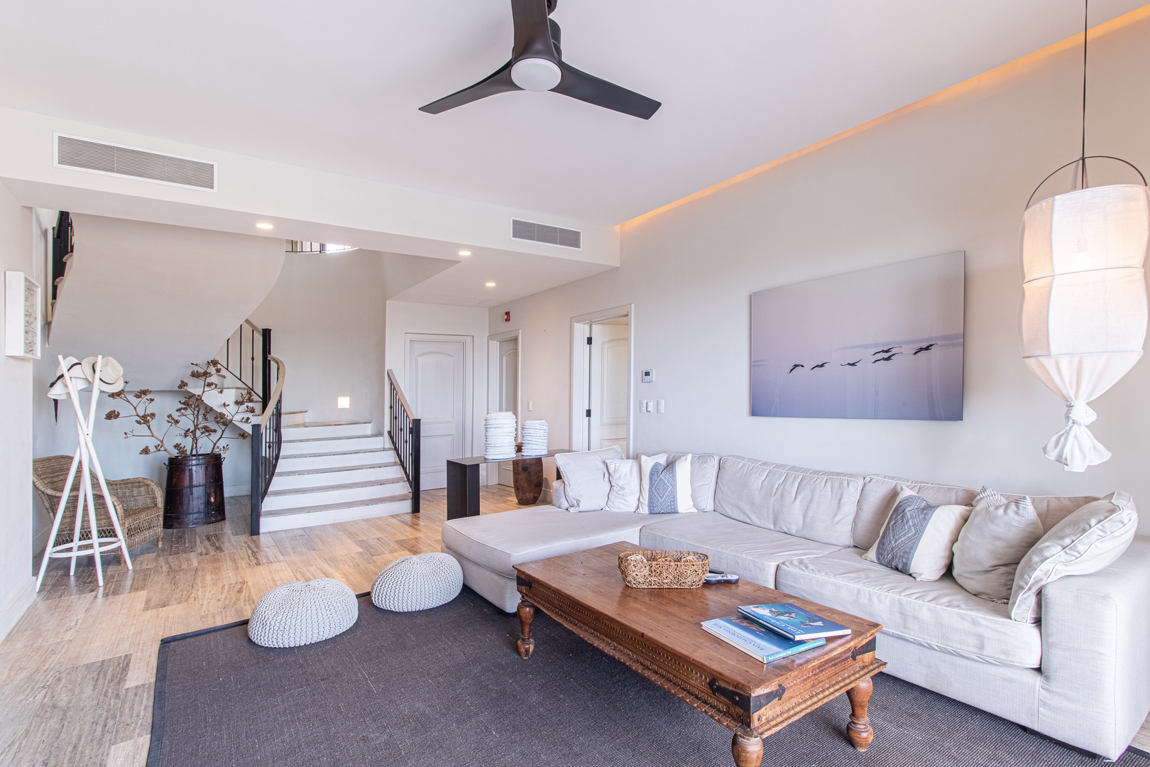 Sink into plush comfort in your coastal-inspired living room, where soft textures, warm wood tones, and serene beach artwork create your perfect retreat after a day of adventure.