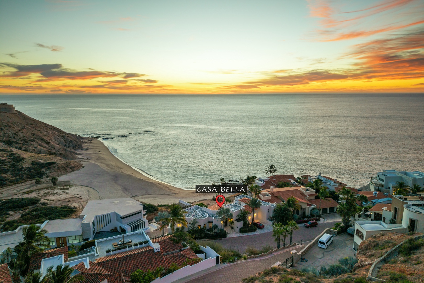 Spectacular aerial view of Casa Bella's beachfront location with golden sunset skies over the coastline.