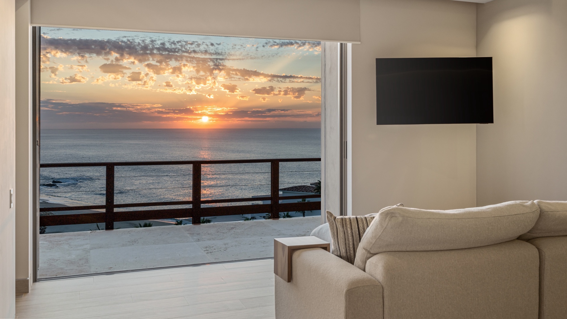 Breathtaking ocean sunset framed by an expansive balcony, blending serene indoor comfort with stunning coastal views—an unforgettable backdrop for your stay.
