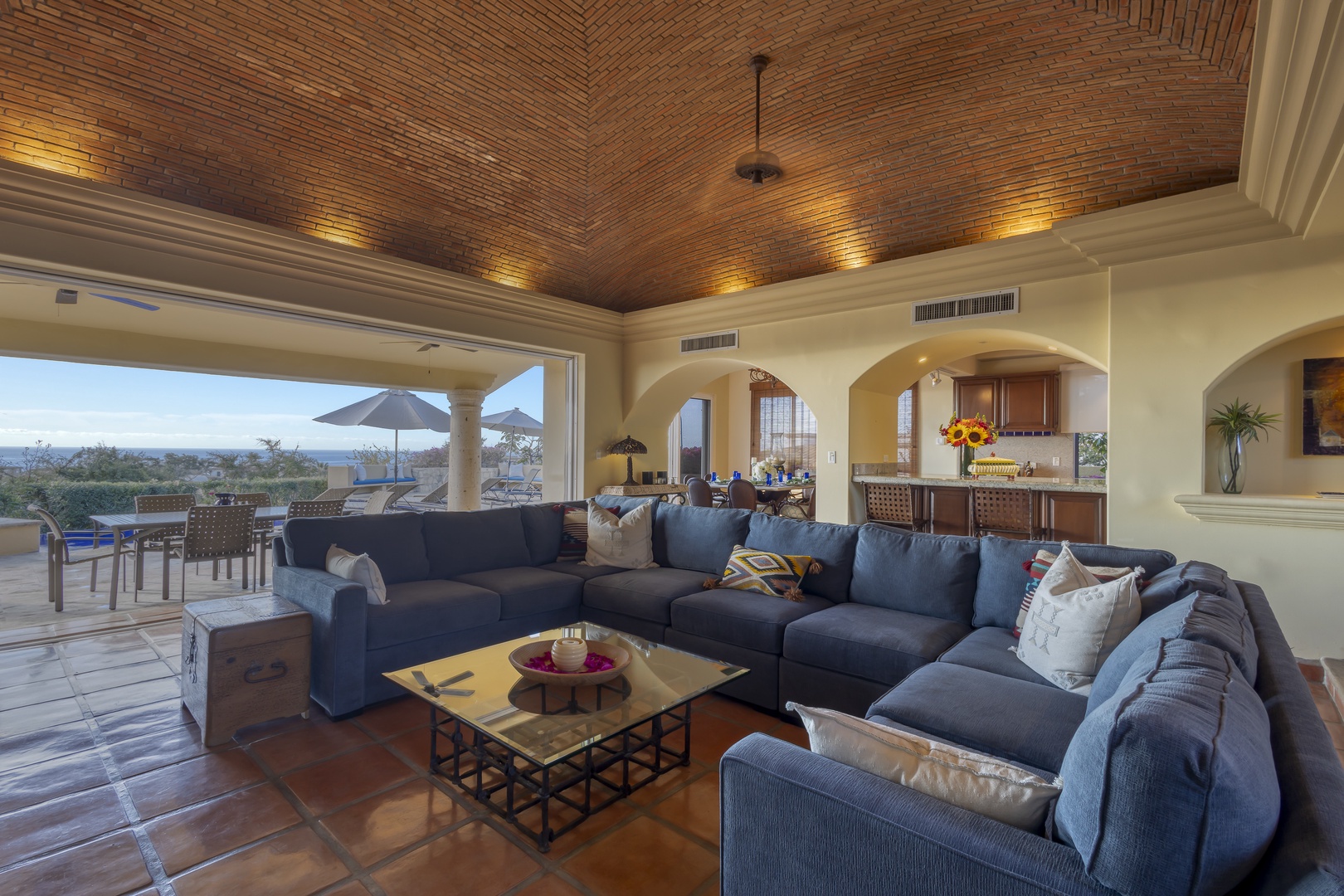 Relax in your elegant living space with vaulted brick ceilings, plush sectional seating, and stunning views of the landscape beyond.