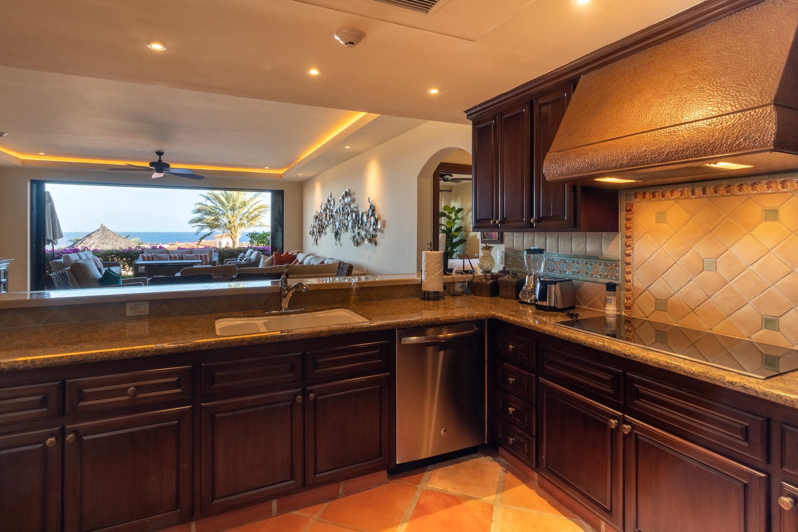 Your gourmet kitchen overlooks a stunning sea view with rich cabinetry and elegant tile accents. Picture yourself preparing meals with the ocean as your backdrop, warm lighting setting a welcoming tone.