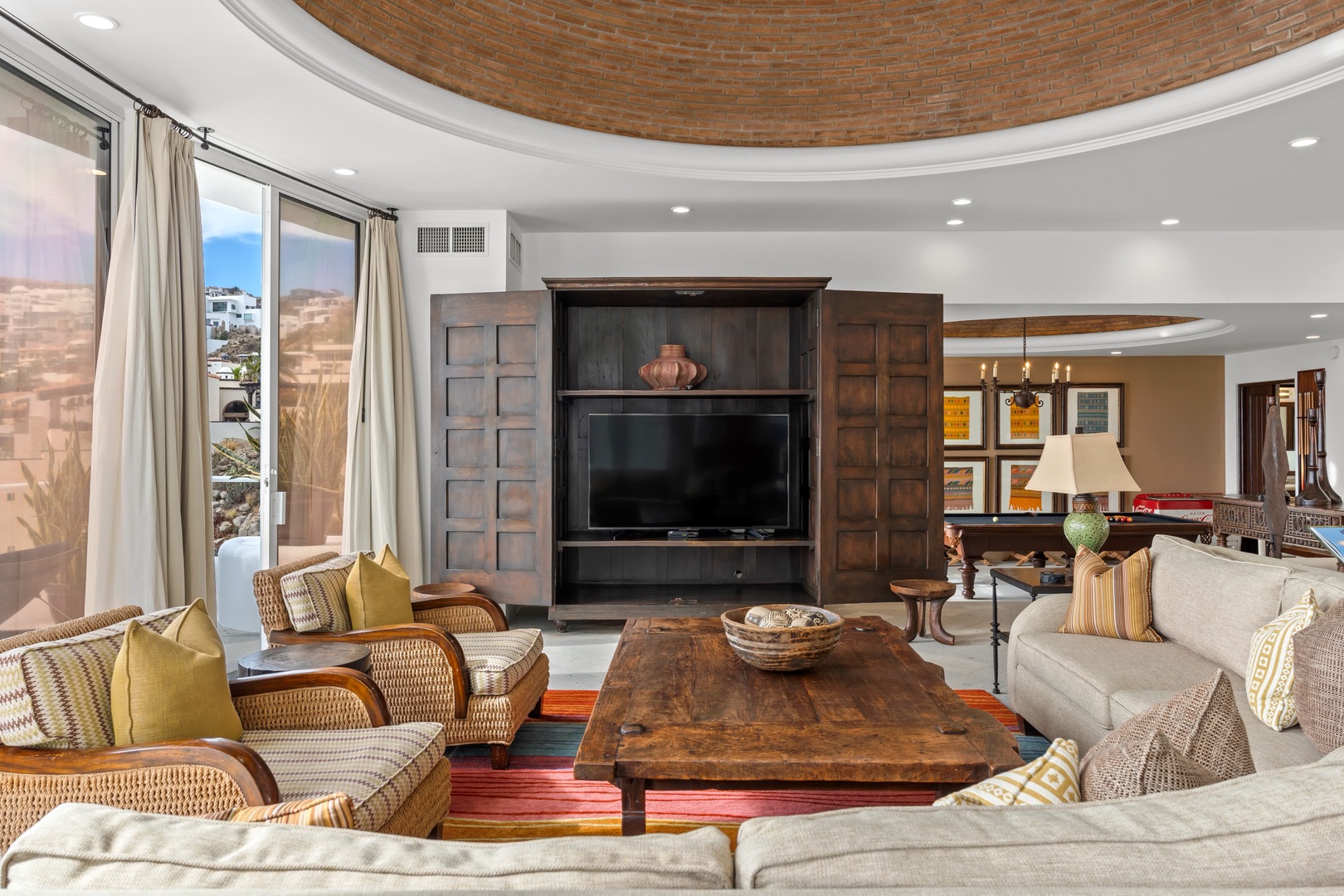 Unwind in this stunning living room where desert views meet elegant comfort through floor-to-ceiling windows and rich wood details.
