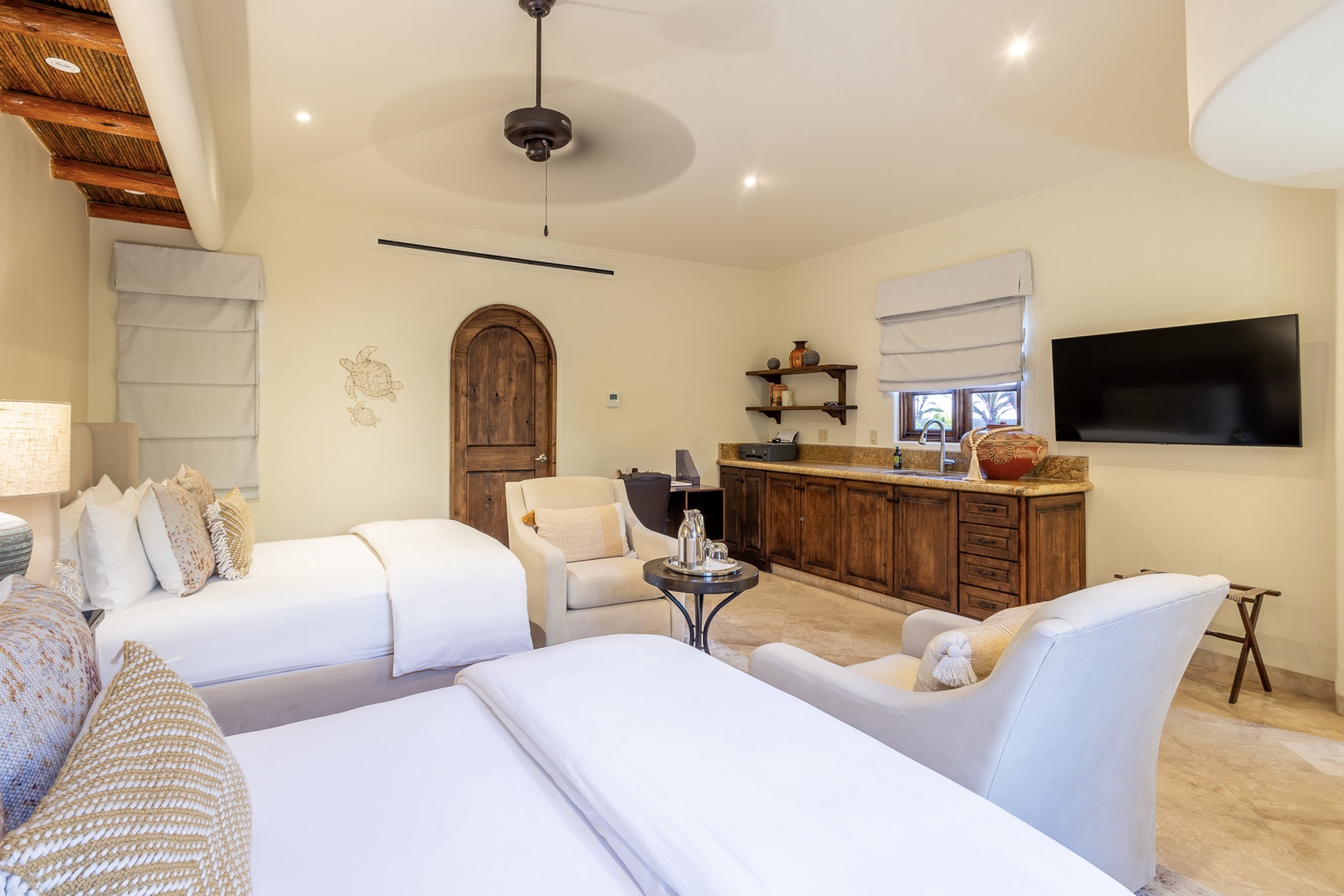 Step into your spacious suite where rustic elegance meets modern comfort. Two luxurious beds await, complemented by a cozy seating area, kitchenette, and entertainment center—all bathed in natural light.