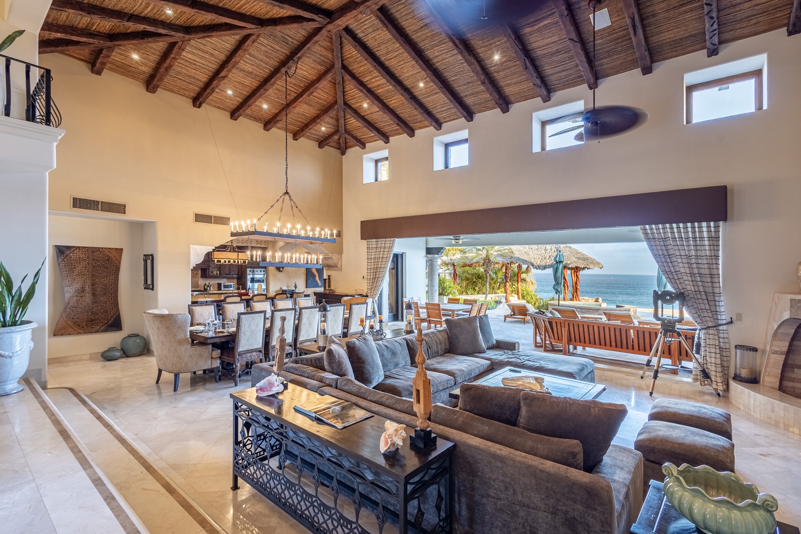 Relax in this stunning open-concept living space with soaring vaulted ceilings and breathtaking ocean views. Unwind in the plush seating area or gather around the elegant dining table, while the sea breeze flows through.