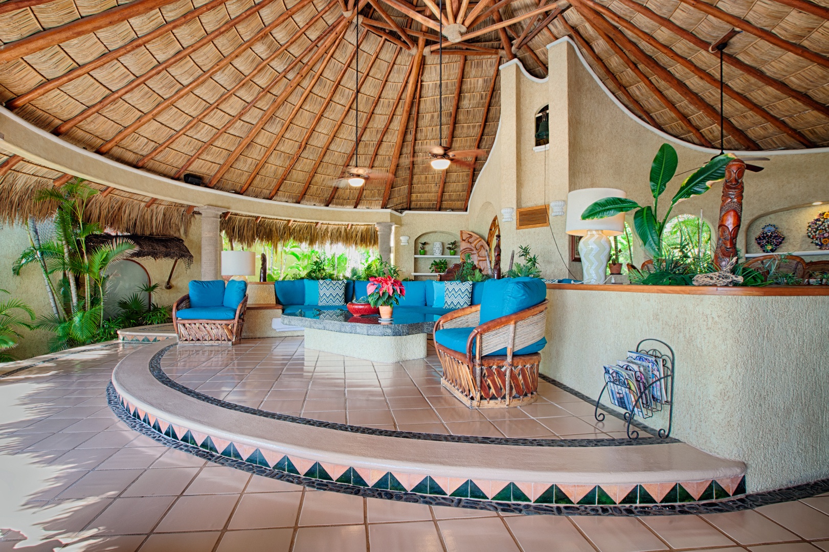 Relax in this stunning palapa-style lobby with vibrant blue seating, tropical plants, and authentic Mexican architecture creating your perfect vacation atmosphere.