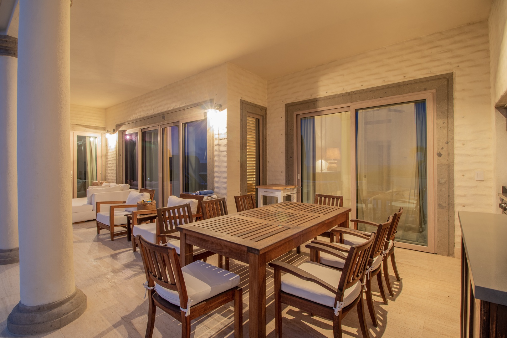 Your private covered terrace awaits, where a handsome wooden dining table invites you to savor meals under soft lighting, seamlessly connecting indoor comfort with outdoor serenity.