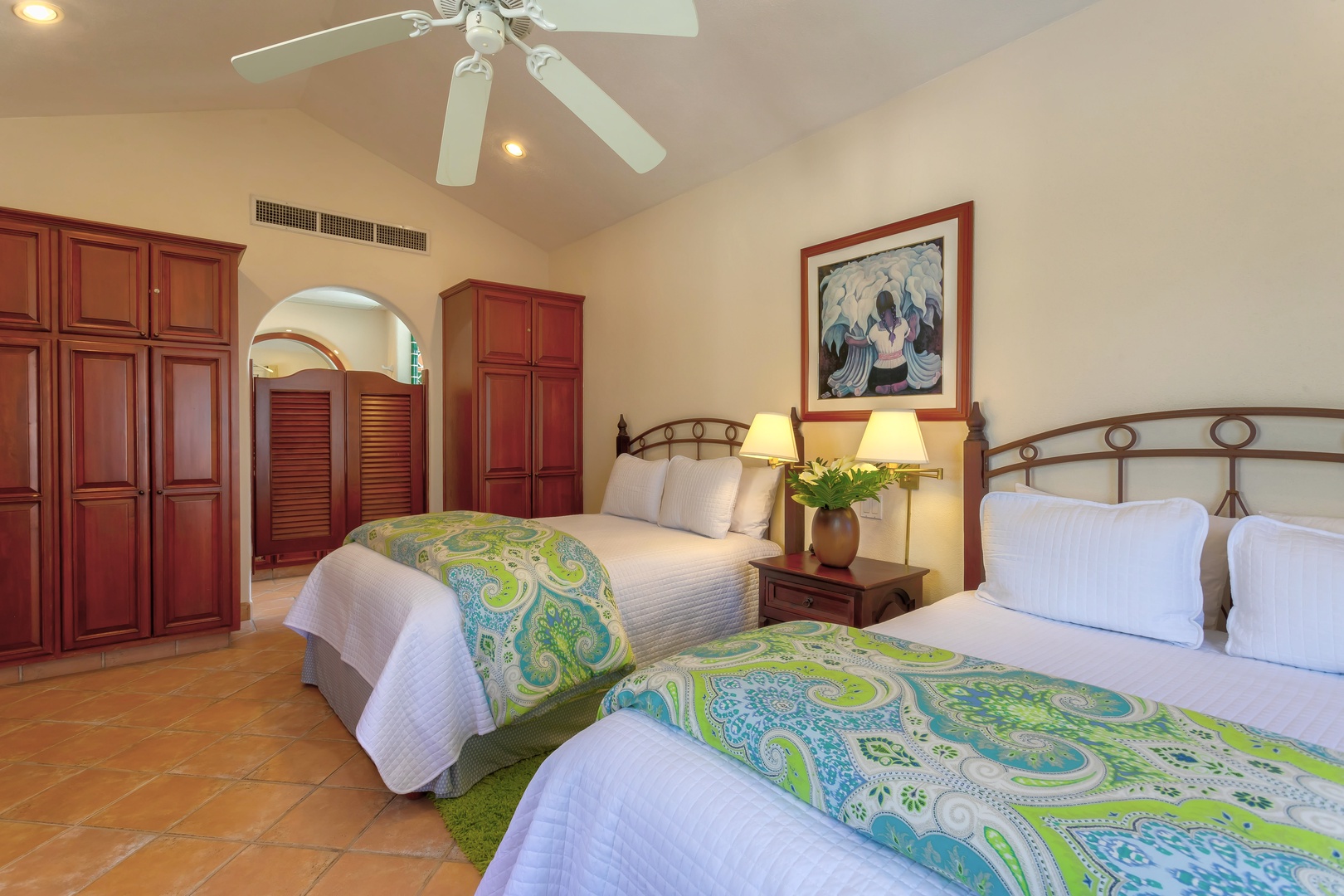 Relax in your spacious bedroom with twin beds, vibrant tropical linens, and rich wood furnishings creating a warm, resort-style atmosphere.