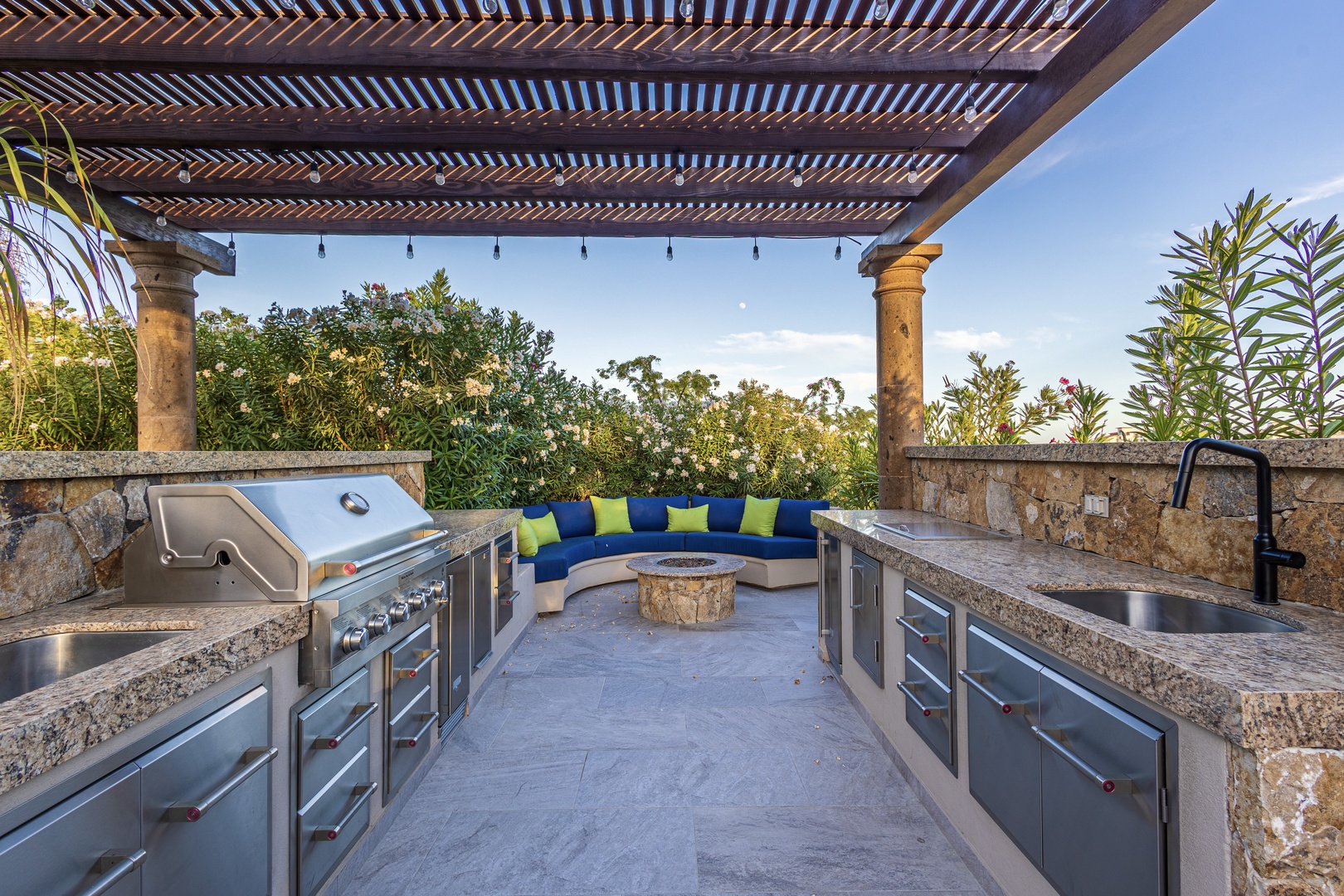 Expansive outdoor kitchen with built-in grill, stone fire pit, and lush garden views—your perfect retreat for al fresco dining and relaxation.