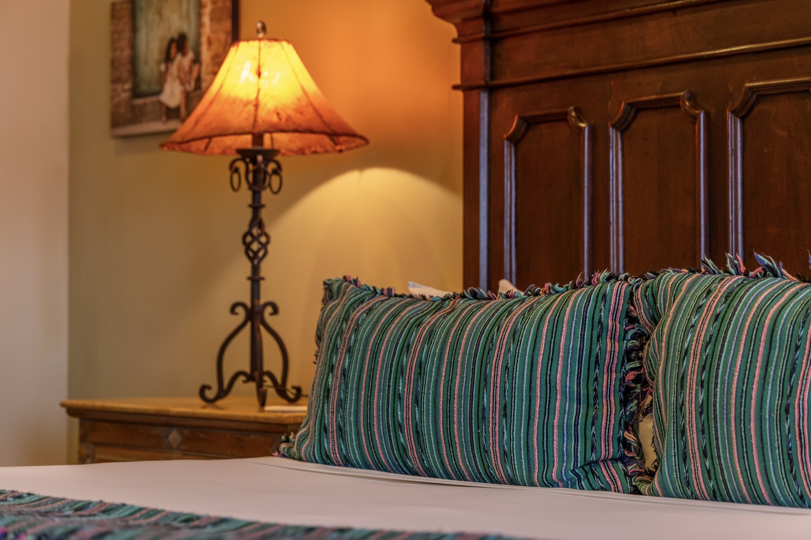 Sink into plush pillows and rest beneath the warm glow of a handcrafted lamp. Your cozy retreat awaits, styled with rustic elegance and inviting comfort for a peaceful night's sleep.