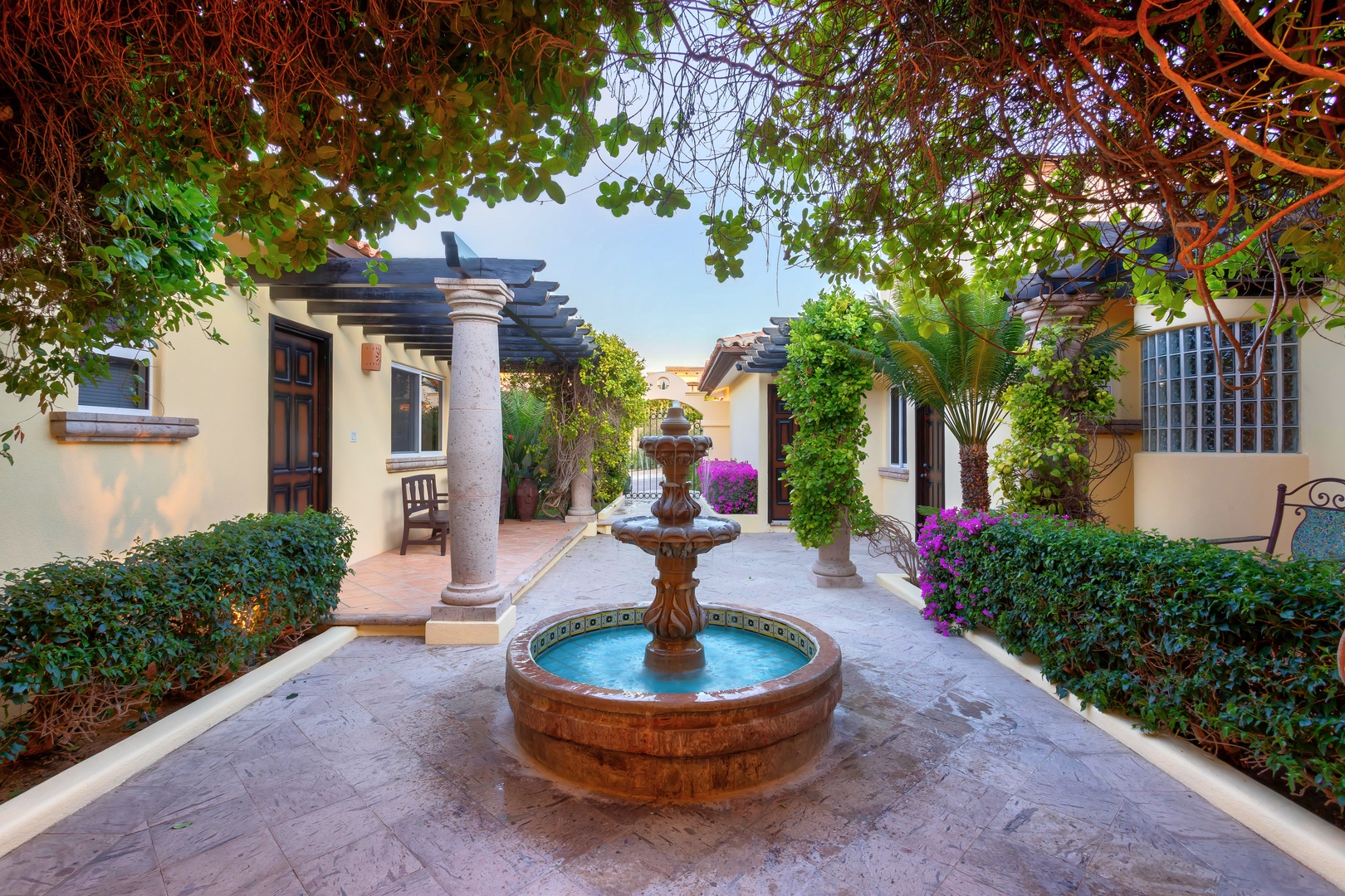 Step into your private courtyard sanctuary, where a charming fountain bubbles peacefully amid lush gardens and colorful bougainvillea.