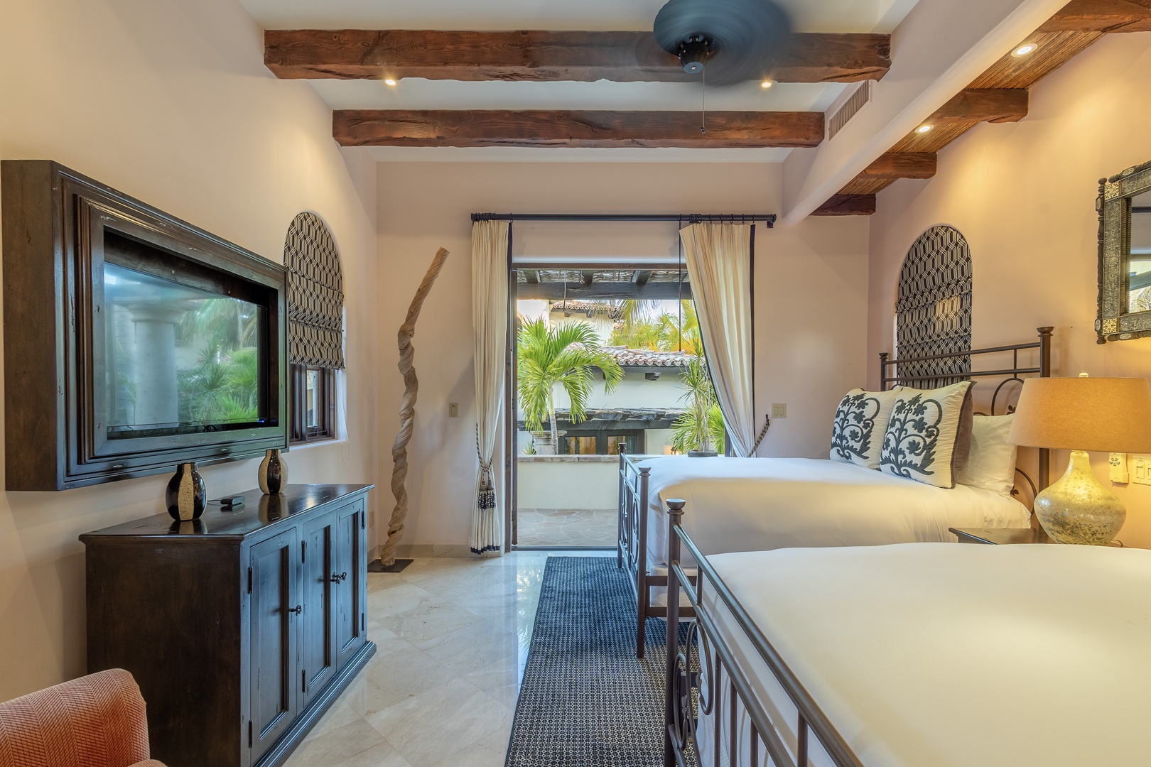 You'll love the rustic-meets-refined charm here: exposed beams, crisp linens on two inviting beds, and a private balcony framing tropical palms—your personal retreat awaits.