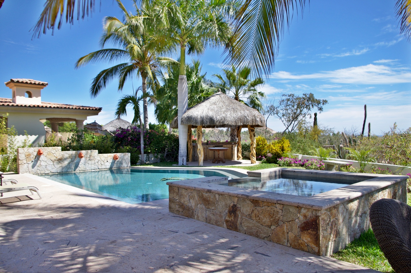 A stunning tropical oasis with heated pool, cascading waterfalls, infinity-edge spa, and thatched palapa bar set beneath swaying palms. Luxury meets paradise here.