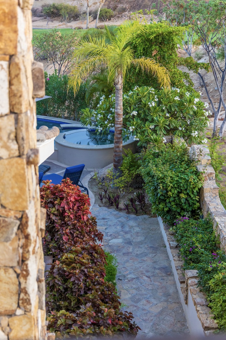 Tropical paradise awaits with a private hot tub nestled among lush palm trees and vibrant flowering plants, creating your perfect outdoor oasis.