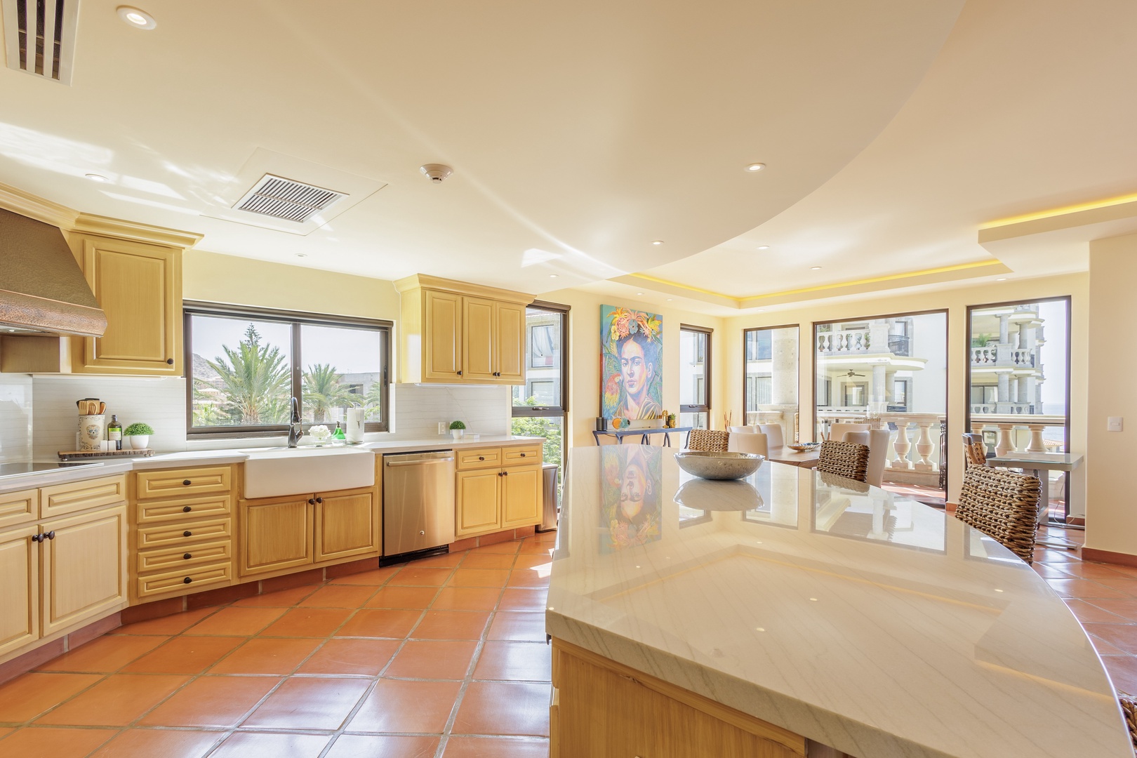 Picture yourself preparing meals in this sunlit gourmet kitchen with warm wood cabinetry, gleaming countertops, and graceful terracotta tile floors flowing throughout your spacious culinary haven.