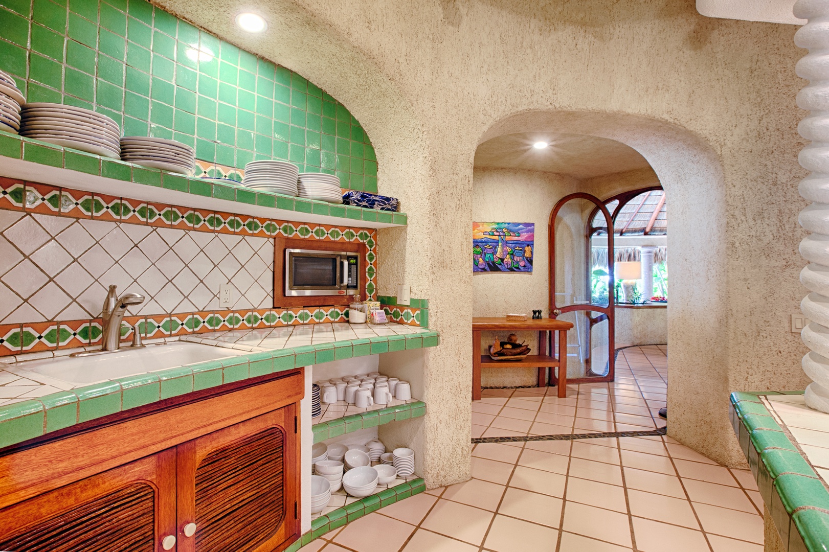 Cook in your beautiful Mexican-style kitchen with vibrant green tiles, built-in microwave, and authentic architectural details creating warm, inviting atmosphere.