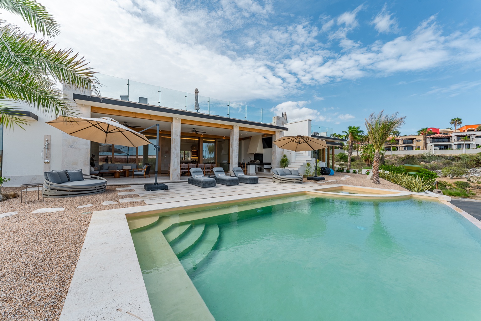 Modern beachside villa with pristine pool and panoramic ocean views. Spacious deck with loungers and umbrella-shaded seating creates your perfect coastal escape.