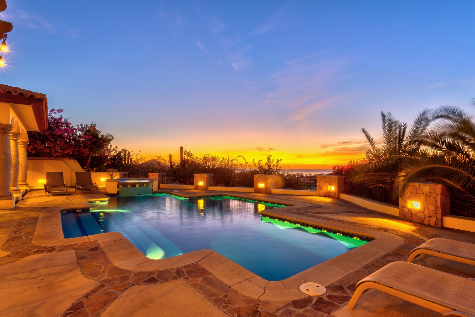 A stunning sunset over the private pool area, surrounded by tropical landscaping and elegant stone architecture.