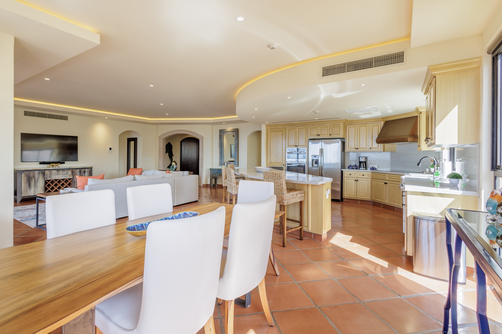 Sunlight fills your gourmet kitchen and open-concept living area, where creamy cabinetry, stainless appliances, and elegant curved ceilings create a spacious, welcoming environment for cooking and gathering.