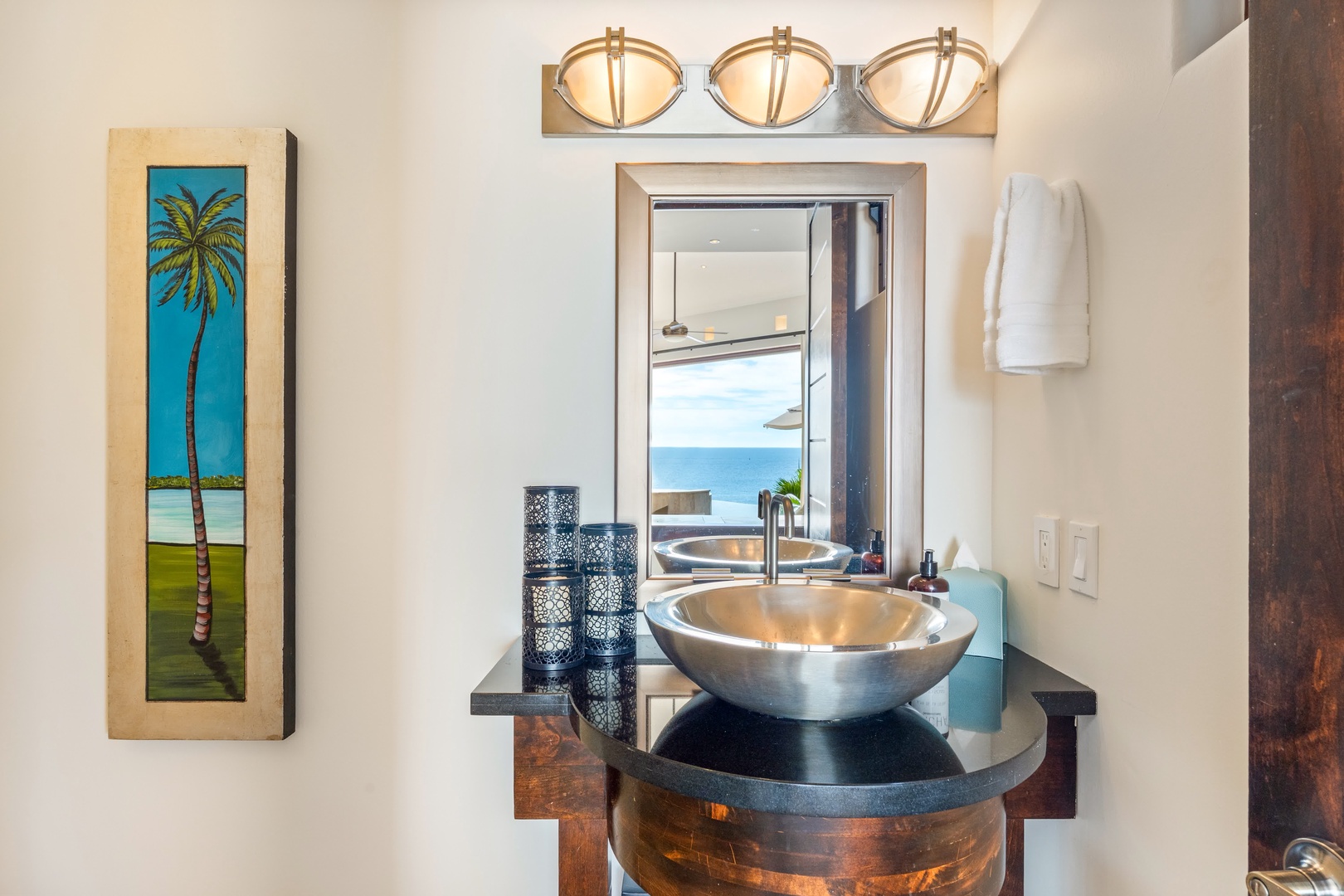 Your elegant bathroom features a striking vessel sink and tropical artwork, creating a sophisticated coastal retreat atmosphere.