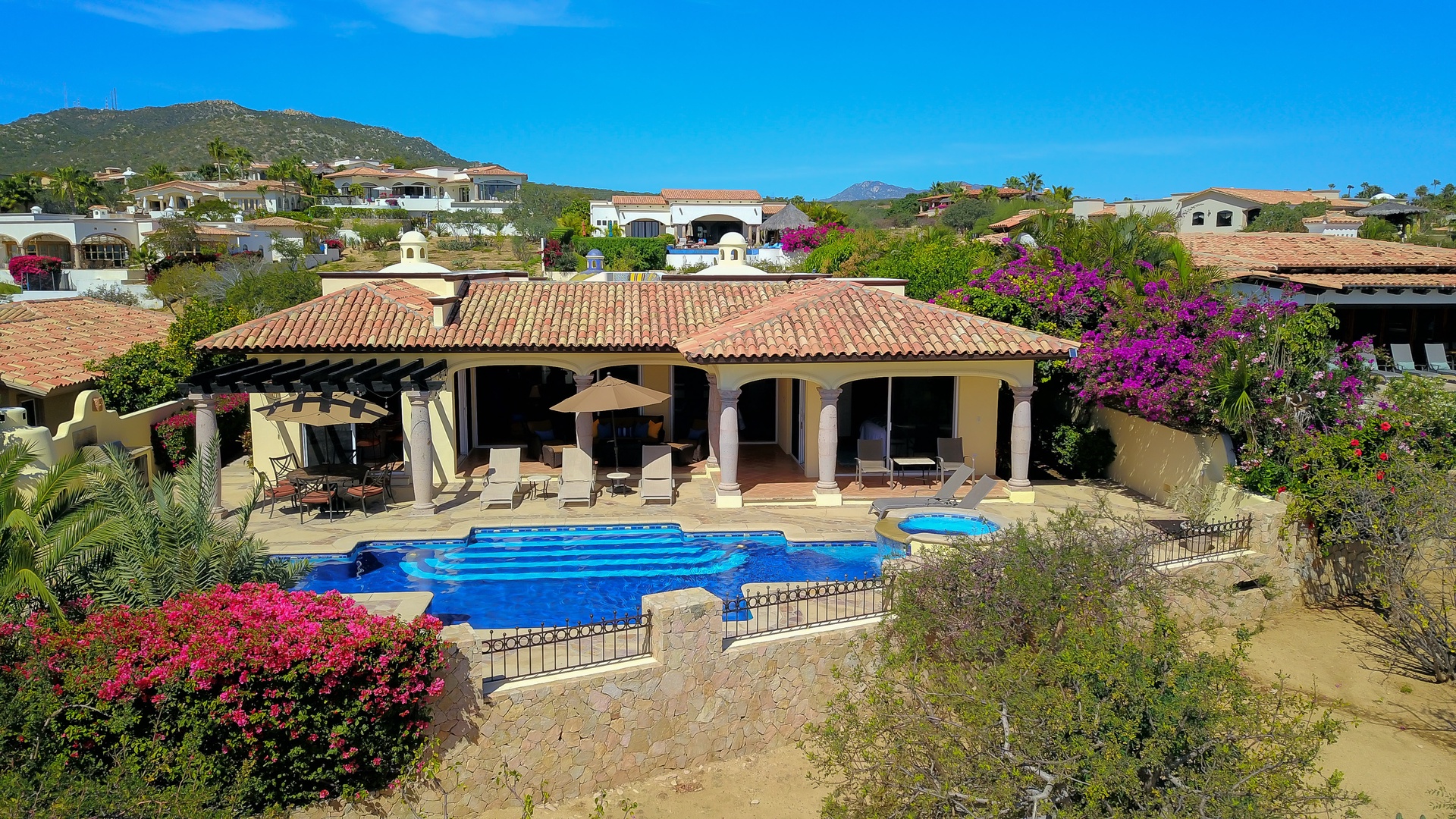 Stunning hillside villa with private pool surrounded by vibrant bougainvillea and desert landscape views.