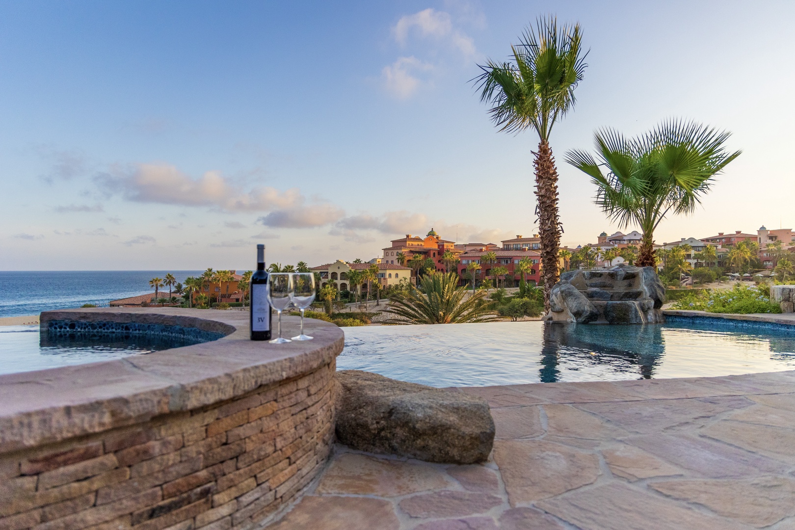 The resort sits along a scenic coastal stretch featuring swimming pools, palm trees, and stunning ocean views.