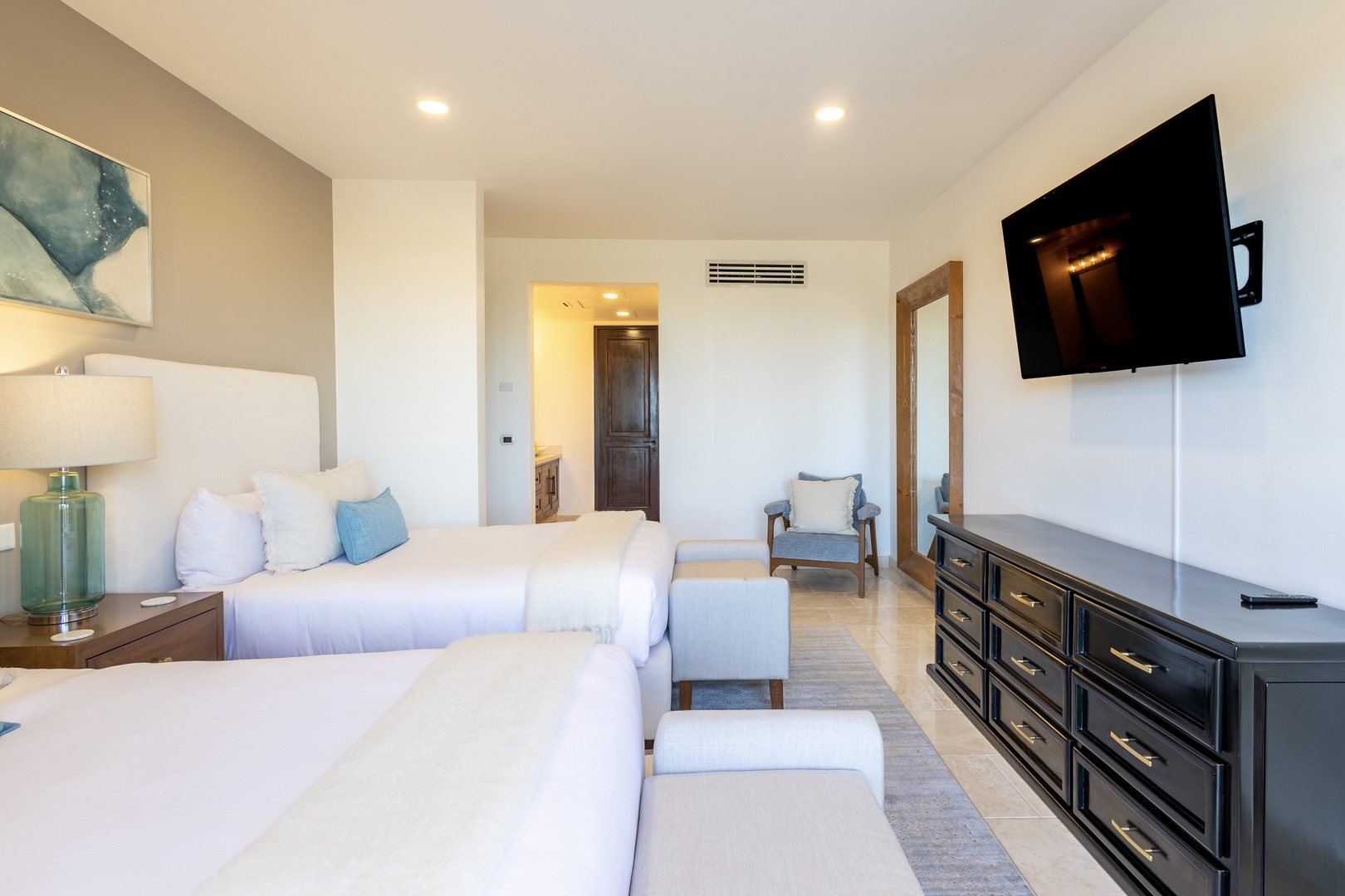 Unwind in your serene bedroom with plush beds, coastal decor, and modern amenities. Cool air conditioning and a mounted TV make your stay comfortable and relaxing.
