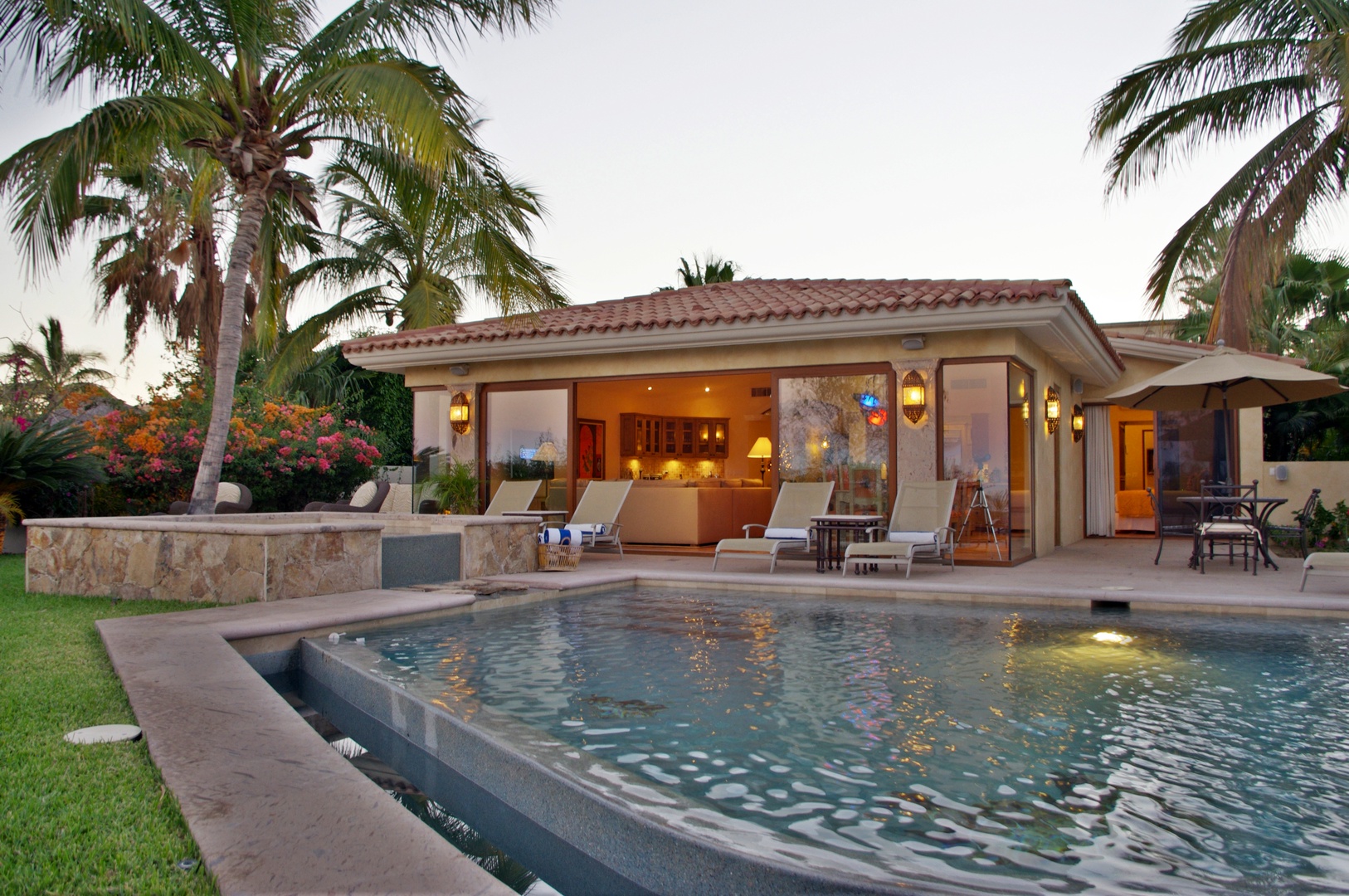 Stunning villa nestled among swaying palms, featuring a private pool and inviting outdoor lounging spaces. The property offers an idyllic tropical retreat with warm evening ambiance and lush garden surroundings.