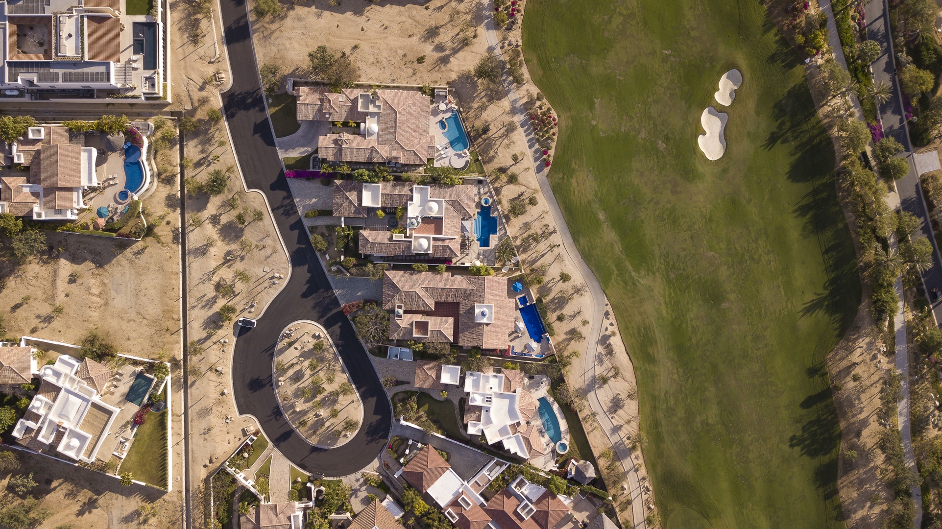 Aerial view showcasing the property's prime location within an exclusive residential community, adjacent to pristine golf course fairways and manicured grounds.
