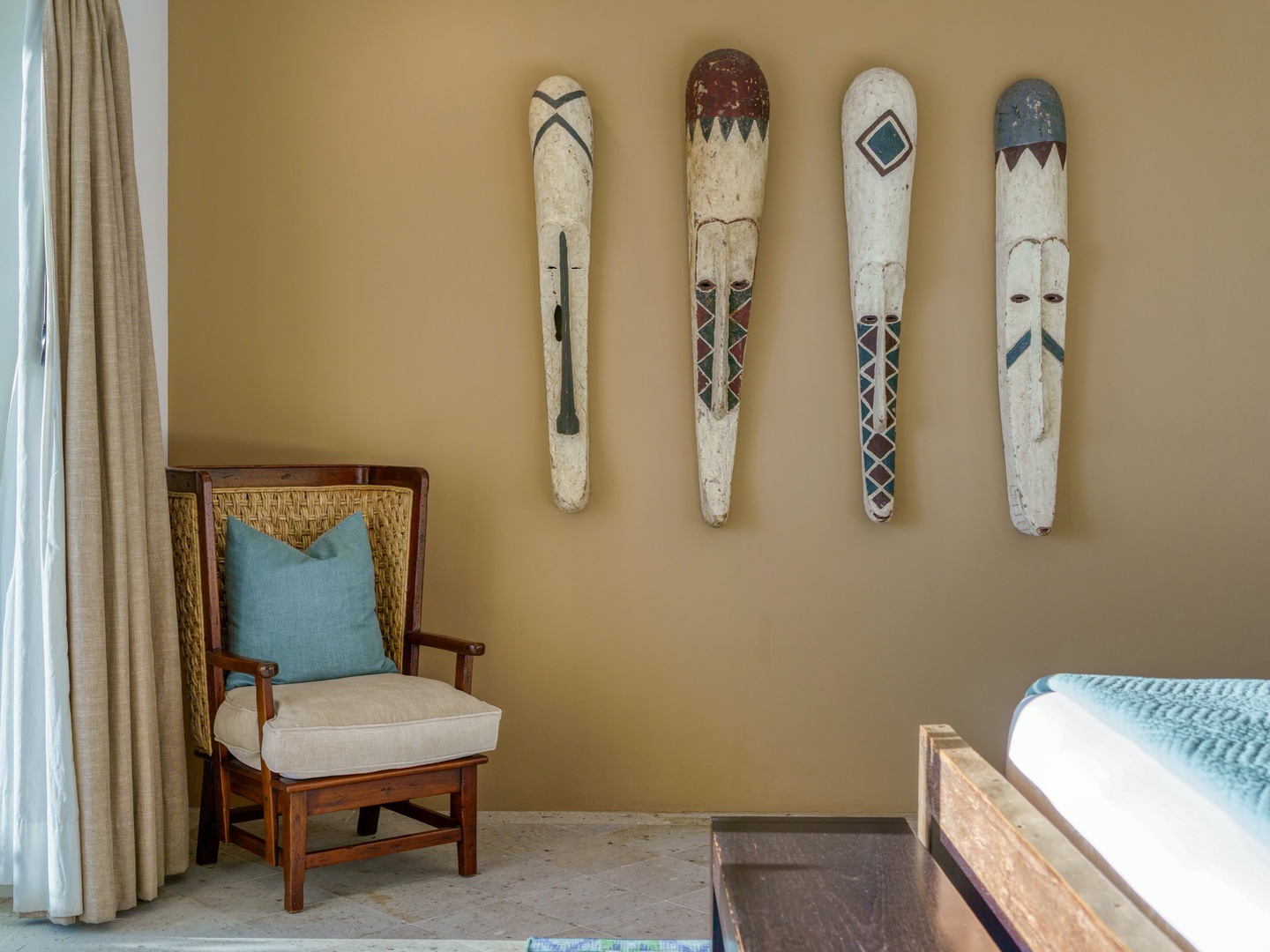 Settle into your private reading nook where authentic tribal masks create cultural charm above your cozy armchair.