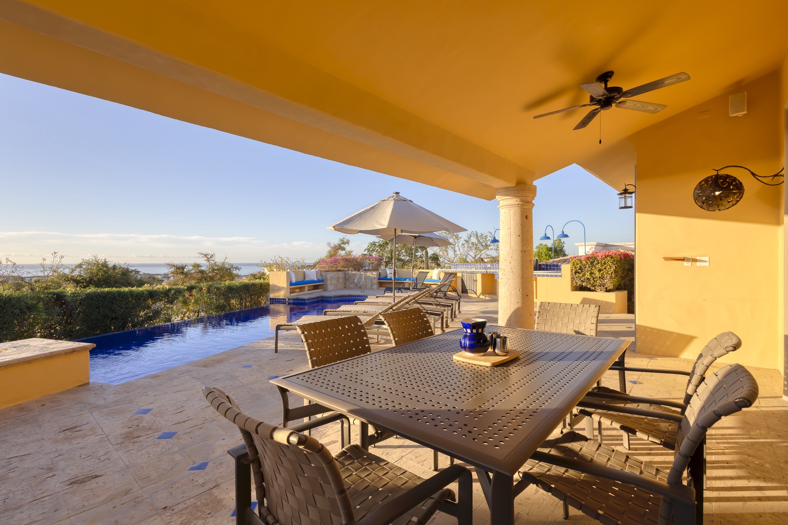 Your covered terrace invites outdoor dining with stunning ocean views, ceiling fan comfort, and poolside relaxation.