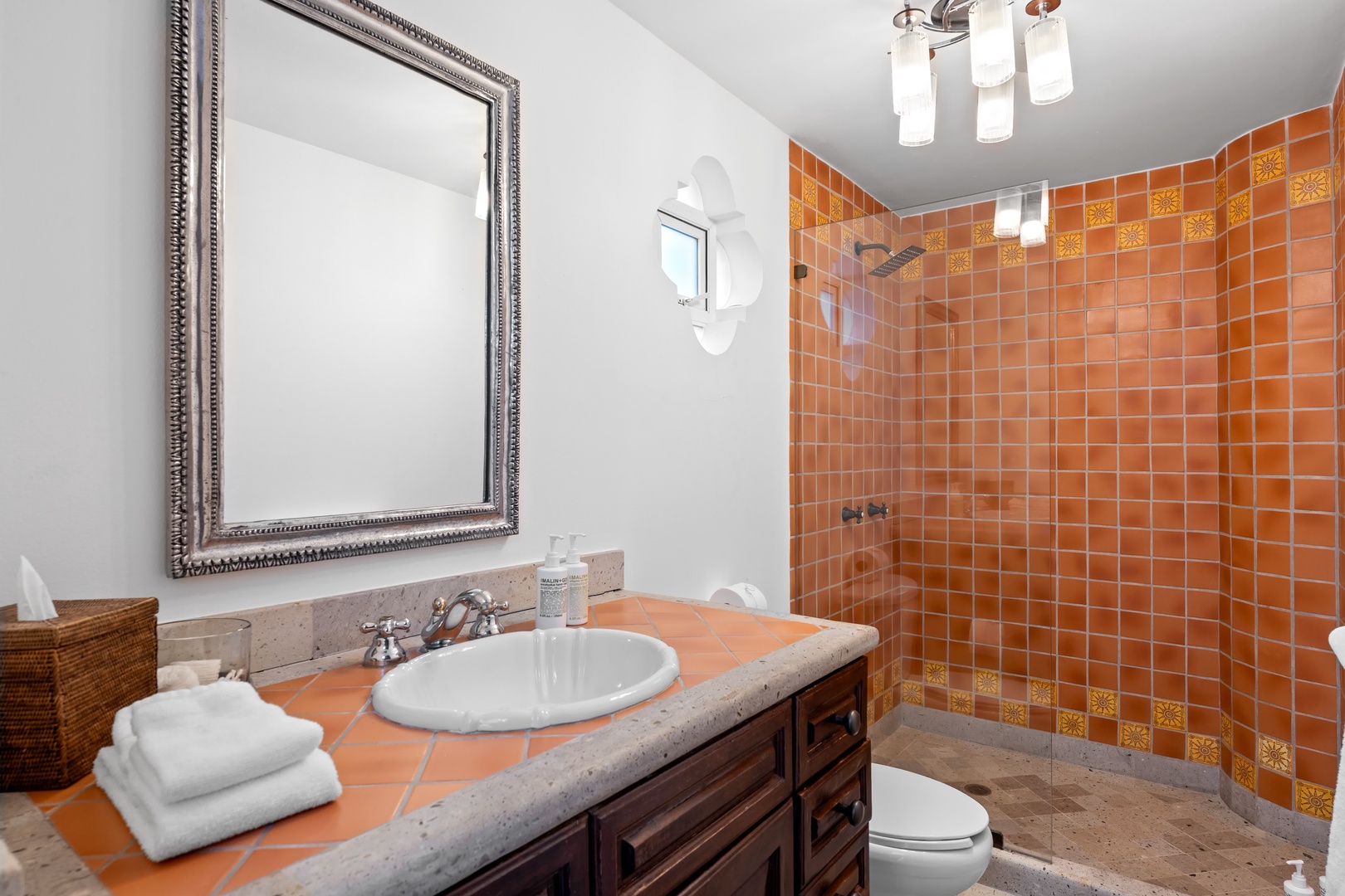 Refresh in your vibrant bathroom featuring warm terracotta tiles, elegant vanity, and rainfall shower—your perfect morning sanctuary.