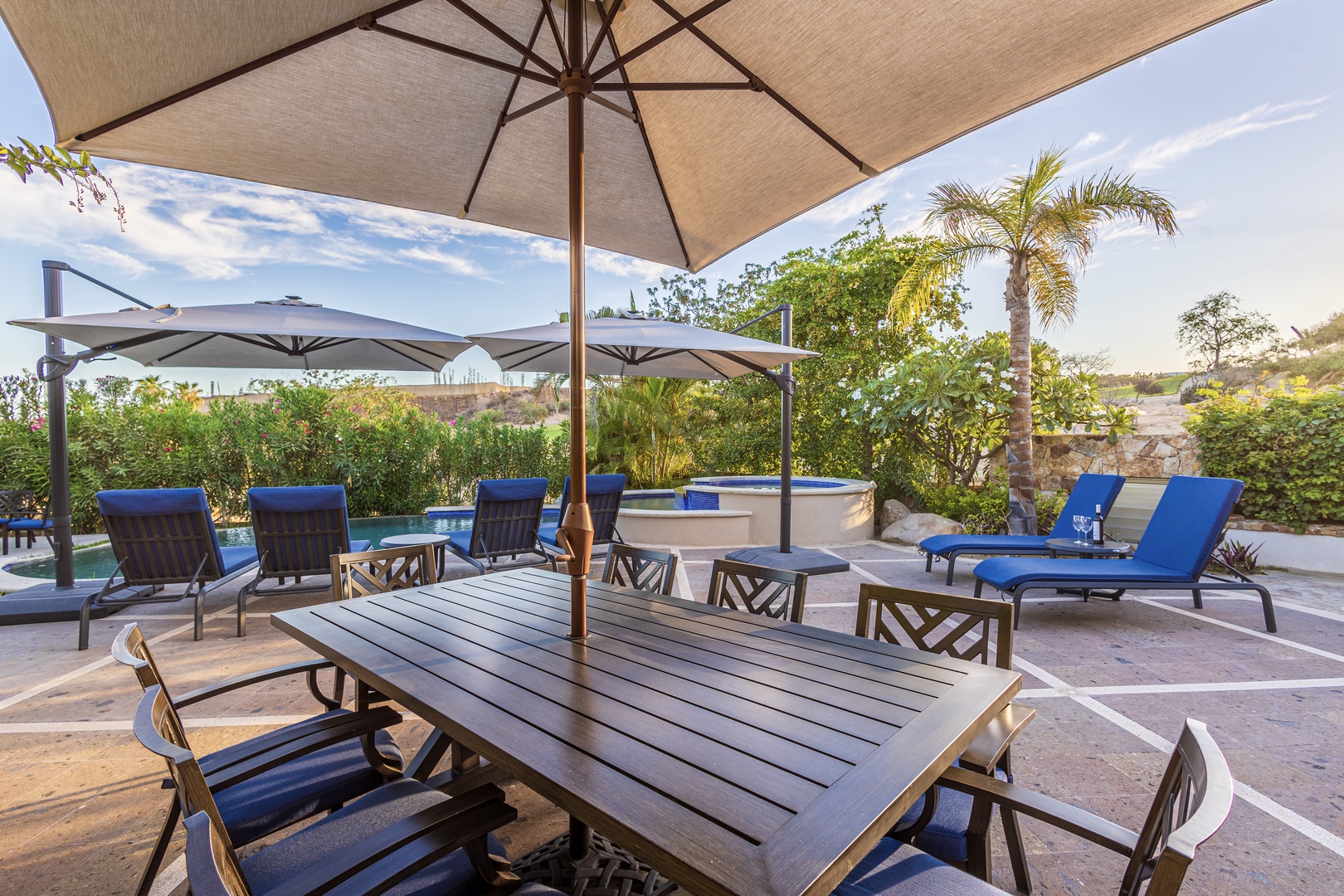Settle into your private poolside oasis, where tropical palms sway overhead and blue lounge chairs await your sunny afternoons beneath the umbrella.