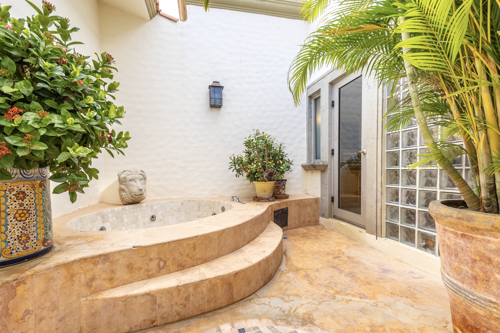 Unwind in your private courtyard hot tub, surrounded by lush tropical palms and vibrant blooms—a serene escape designed just for you.