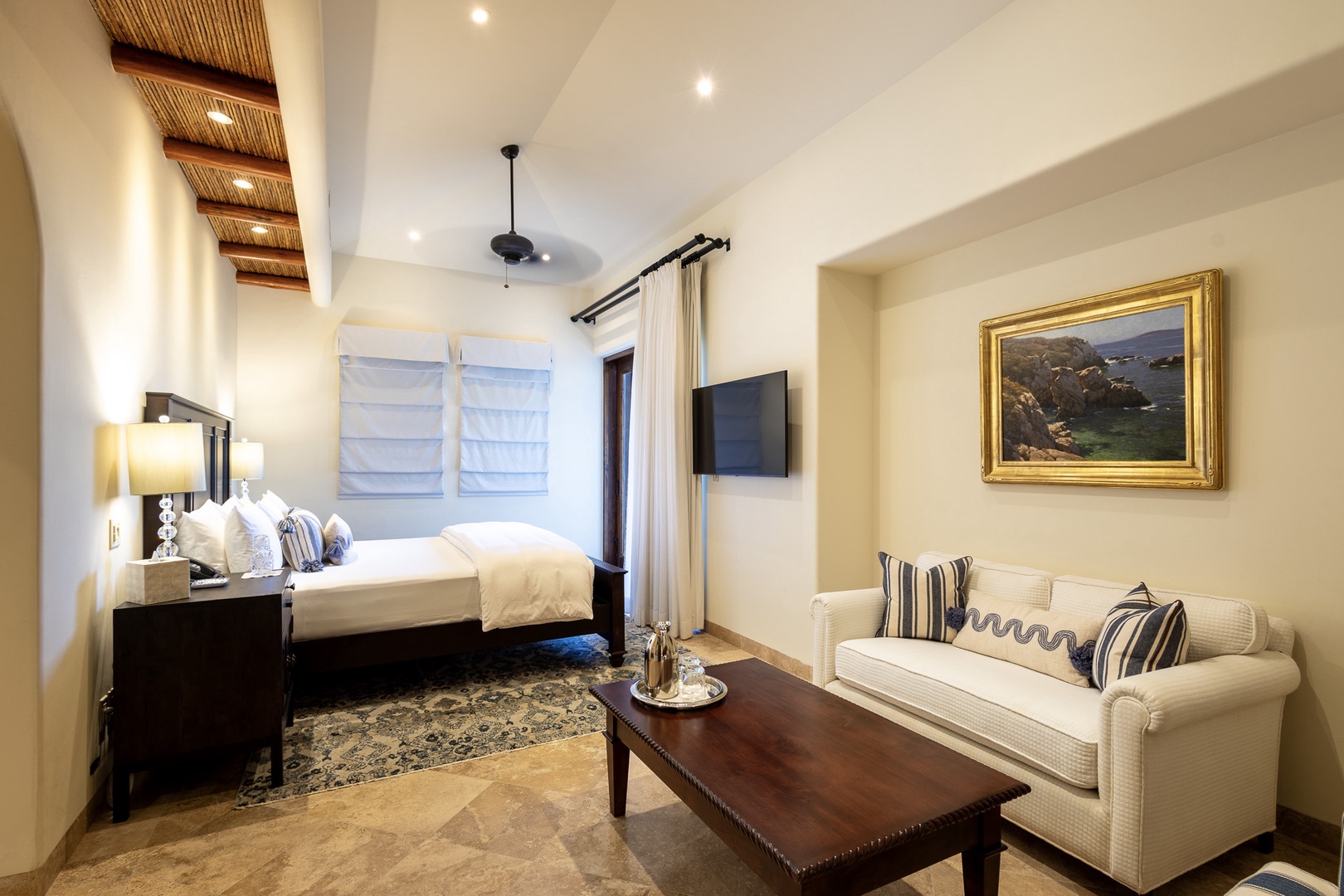 Relax in your spacious suite featuring elegant vaulted ceilings with bamboo accents, plush bedding, and a cozy seating area—your perfect retreat after a day exploring.