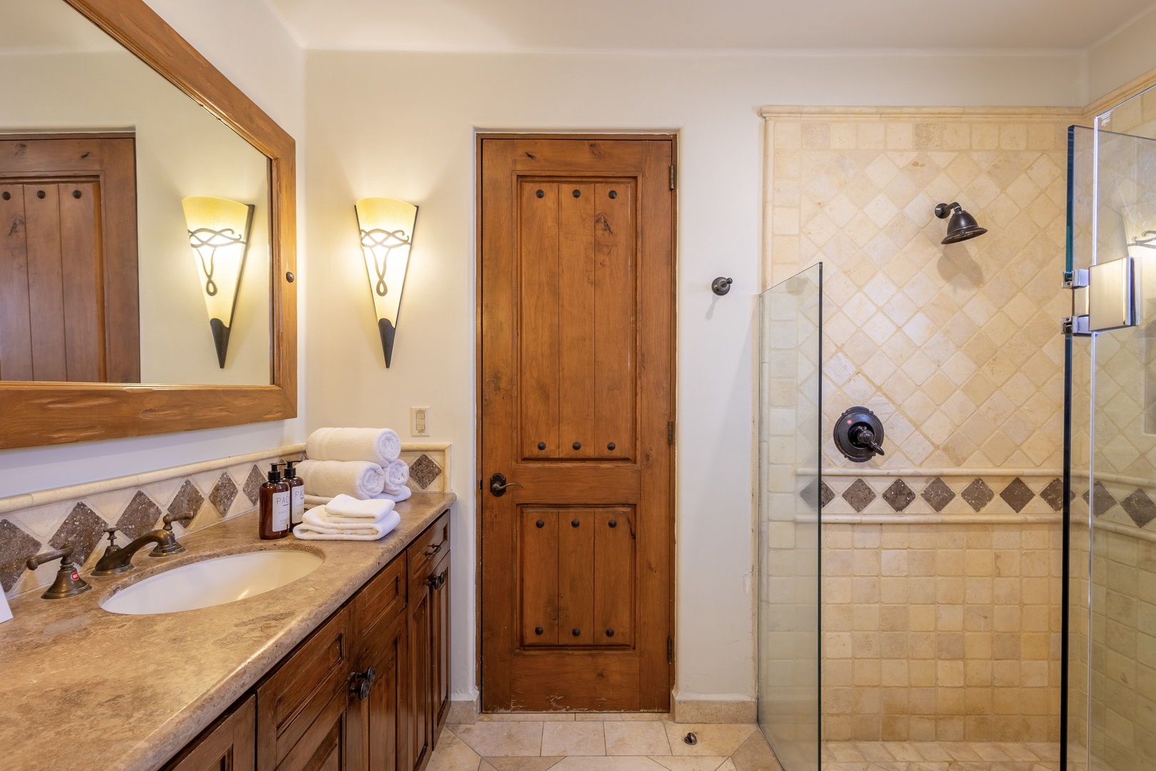 Unwind in your private bathroom featuring warm wood accents, elegant tile work, and a spacious glass-enclosed shower perfect for refreshing after mountain adventures.