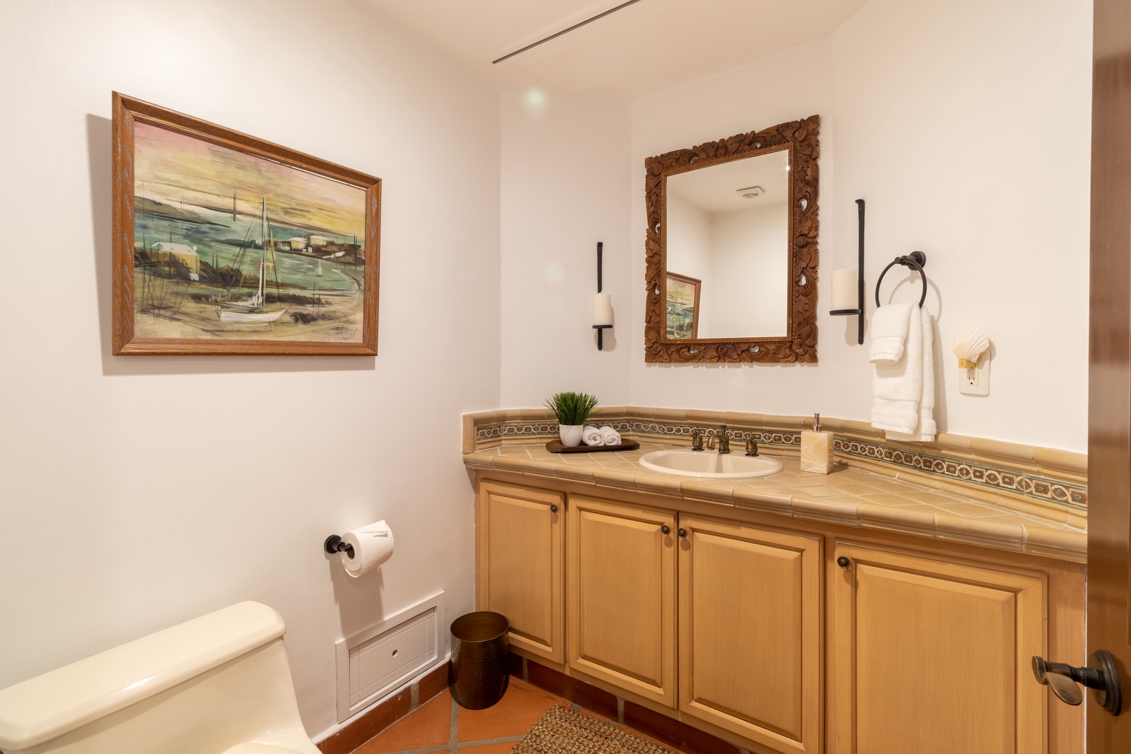 Picture yourself unwinding in this serene bathroom, where coastal artwork and warm tile accents create a welcoming retreat. Plush towels and thoughtful touches make every moment here feel like a spa escape.