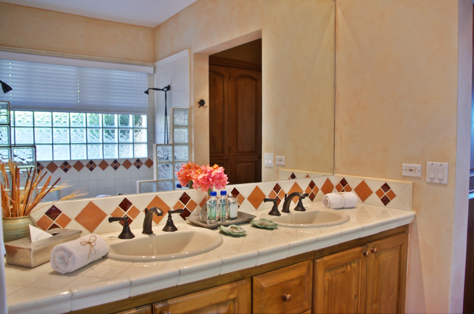 Step into your private bathroom featuring a spacious double vanity with colorful tile accents, plush towels, and thoughtful amenities waiting for you.