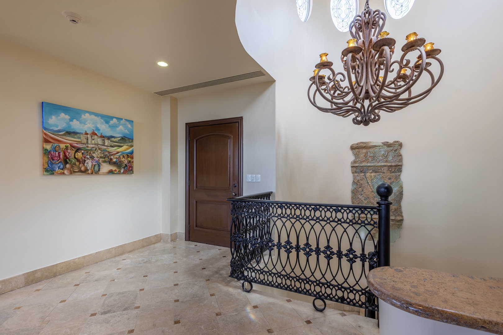 A sophisticated arrival experience awaits, showcasing elegant ironwork balustrade, an ornate chandelier, and refined architectural details that set the tone for your stay.