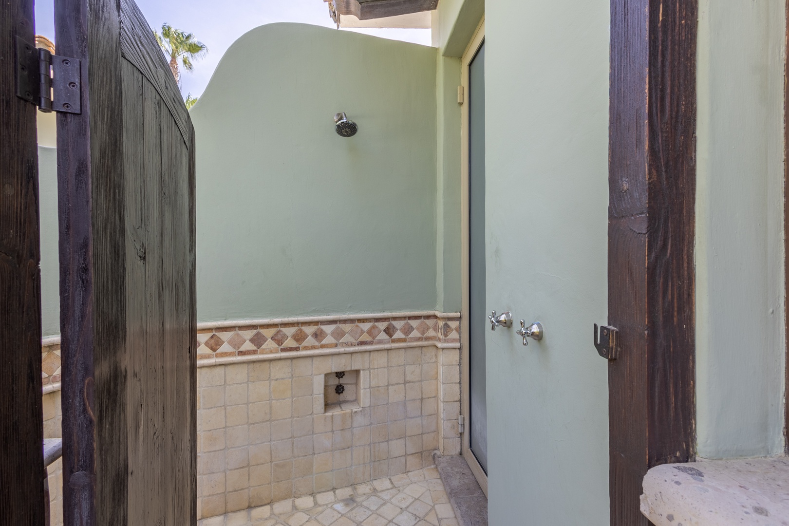 Step into your private outdoor shower oasis, where natural stone tiles and rustic wood create a spa-like retreat under the open sky.