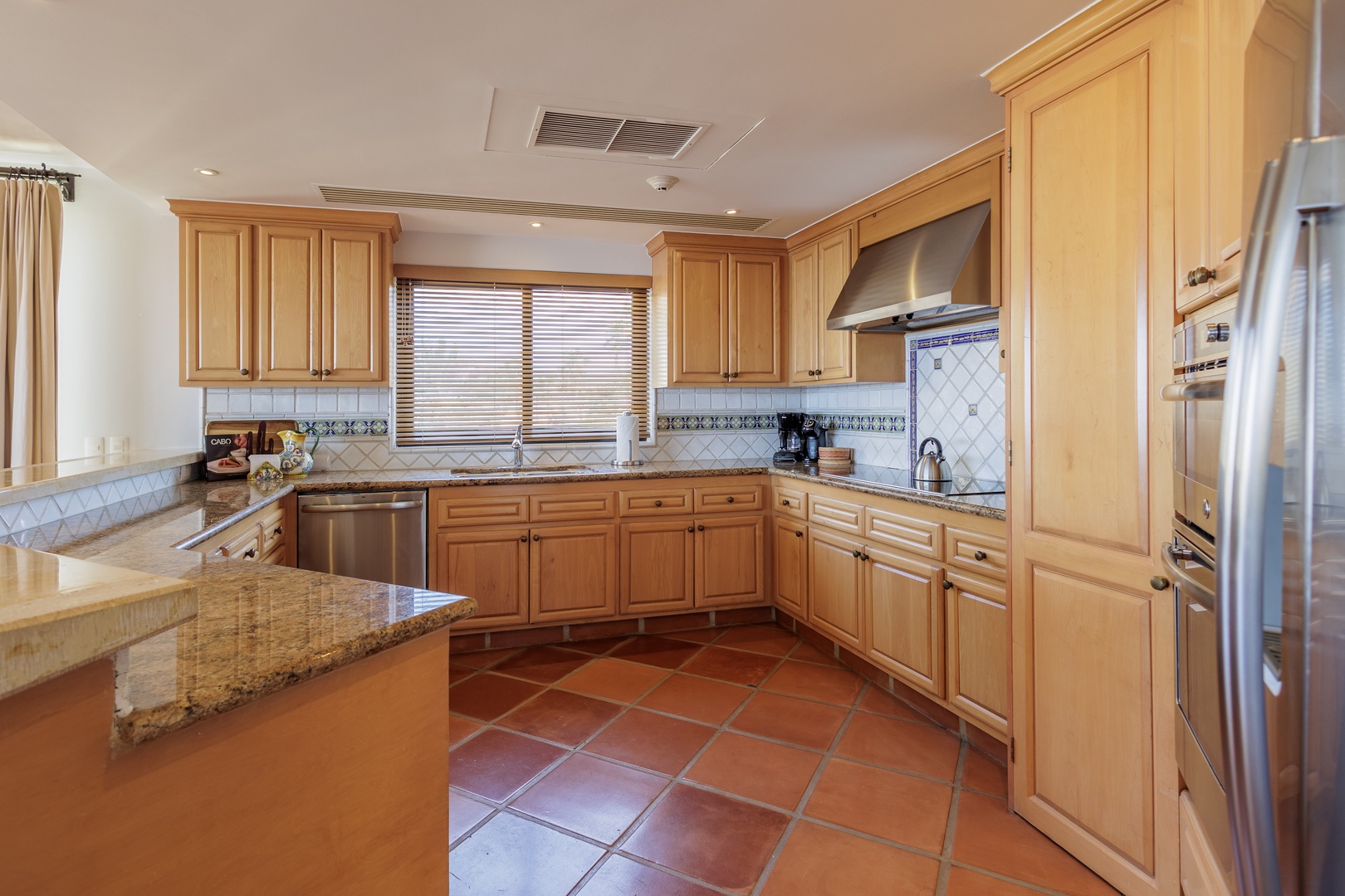 Step into your fully equipped kitchen, featuring granite countertops, elegant tile work, and modern appliances, perfect for preparing delicious meals during your getaway.