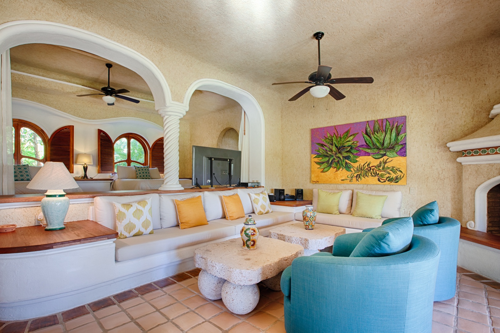 Relax in your beautiful living space with colorful artwork, comfortable seating, and elegant arched details creating a warm Mexican-style atmosphere.