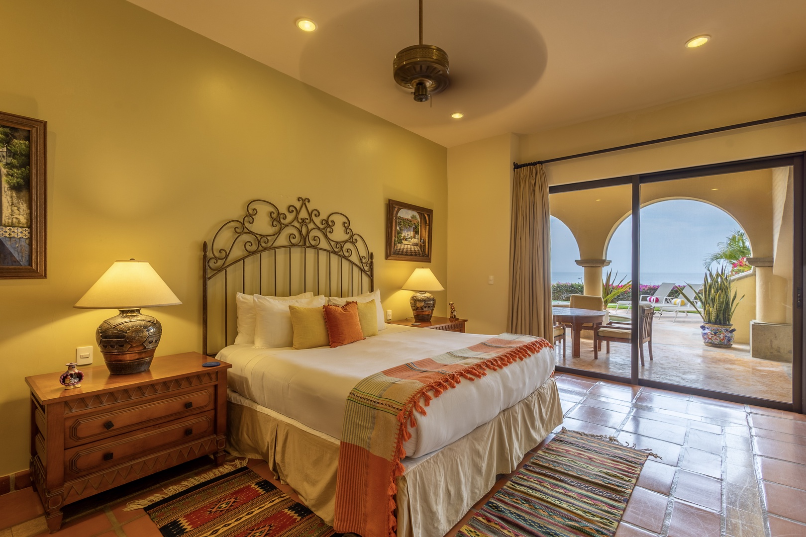 Your serene bedroom opens to a private terrace with archway views, where warm tile floors and artisan furnishings create a peaceful coastal escape.