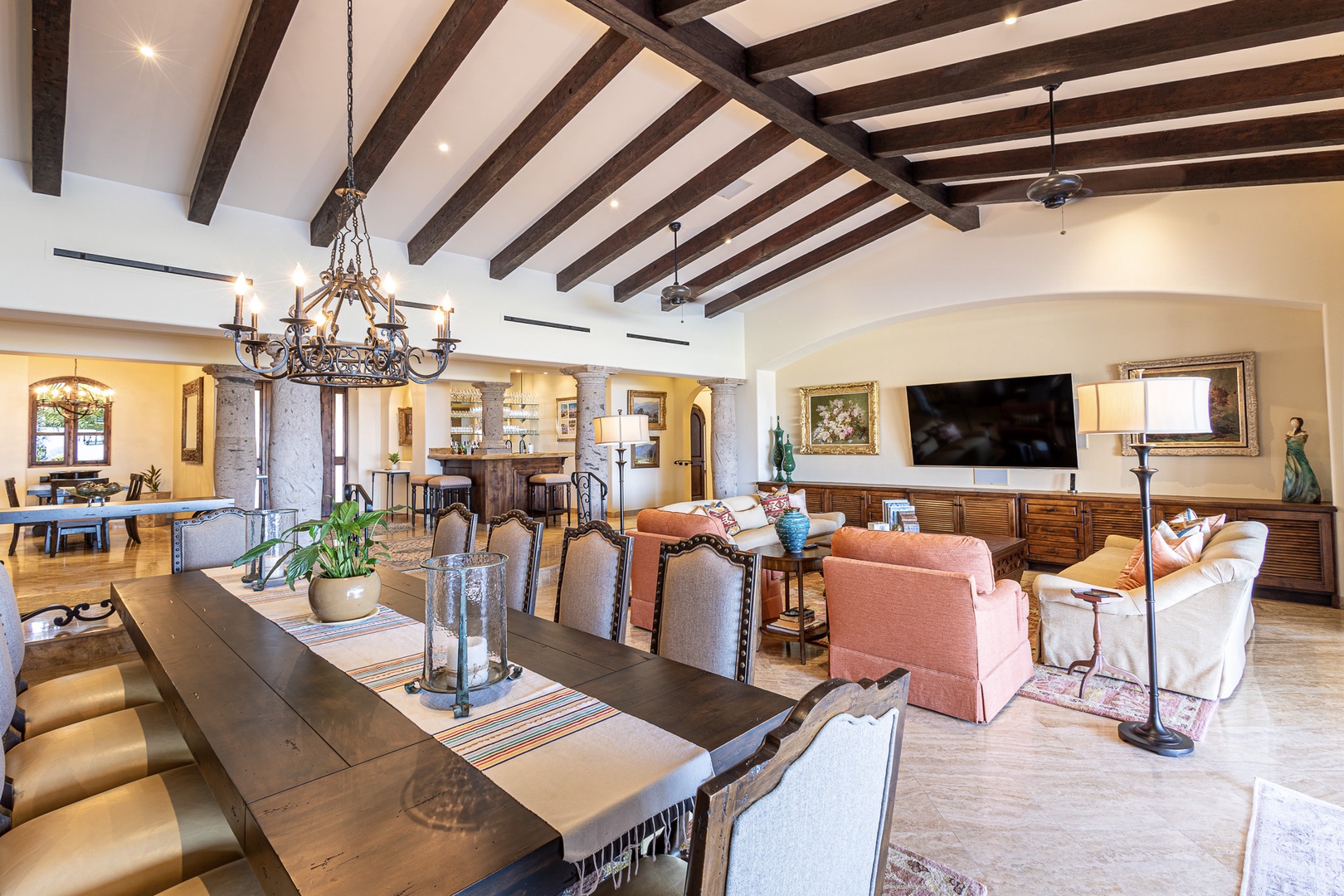 Gather with your loved ones in this stunning open-concept living space, where rustic wooden beams, elegant chandeliers, and warm Mediterranean touches create the perfect backdrop for unforgettable vacation memories.