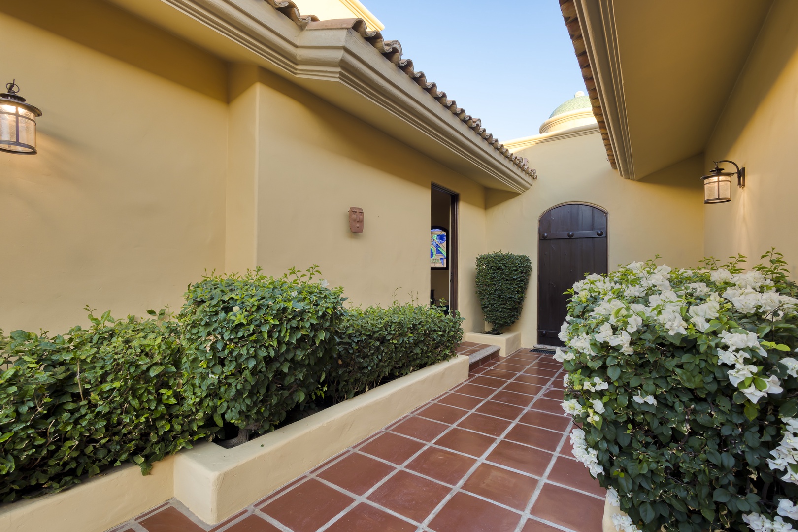 Welcome home to your private entrance, framed by beautiful white blooms and manicured hedges on classic tile flooring.