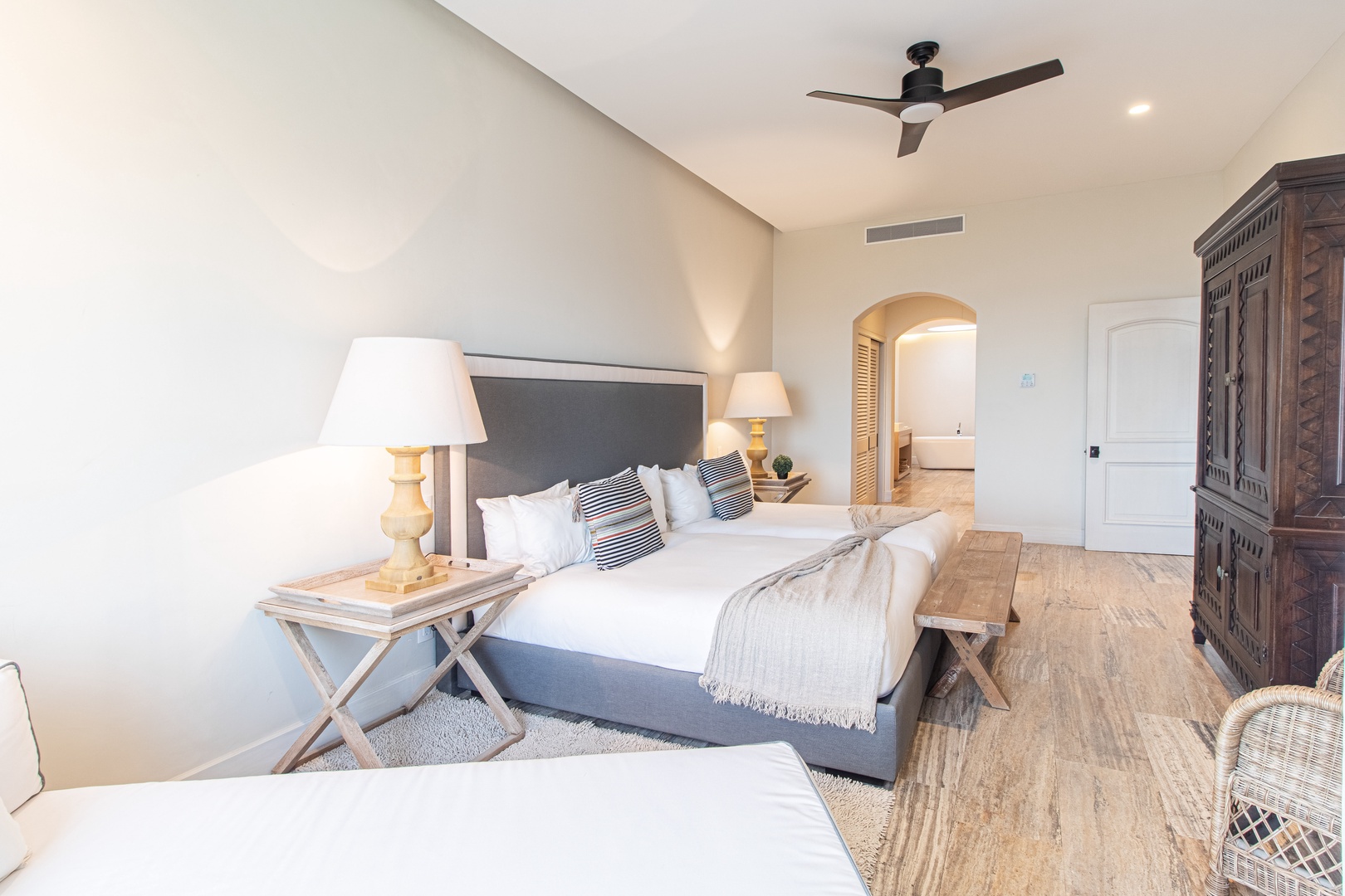 Relax in this serene bedroom where coastal elegance meets comfort. Soft linens, warm wood tones, and gentle ceiling fan breezes create your perfect retreat after a day of adventure.