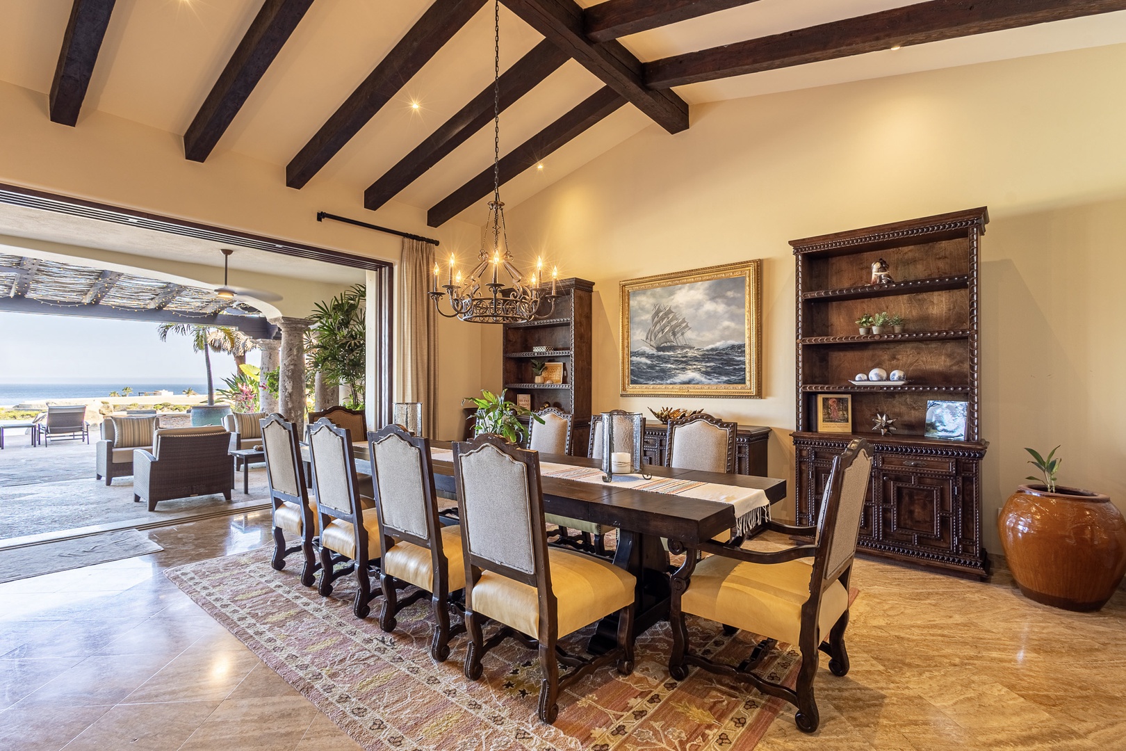 Gather around this elegant dining table under rustic exposed beams, where ocean breezes and stunning views set the stage for your most memorable meals together.