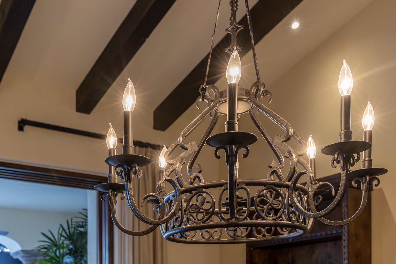 Your elegant chandelier casts a warm glow across the vaulted ceiling with its charming exposed beams, creating an inviting ambiance for your stay.