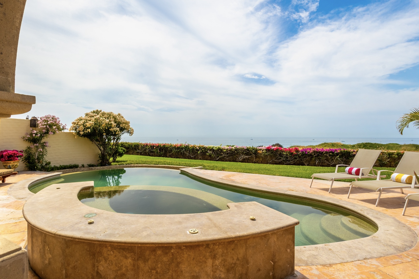 Picture yourself lounging poolside, soaking in the warmth as vibrant gardens frame your private ocean view—an idyllic escape awaits.