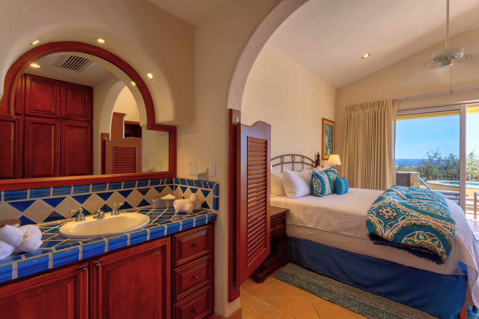 Your vibrant suite blends Mexican charm with ocean views, featuring handcrafted tile work and a cozy bed draped in colorful linens.